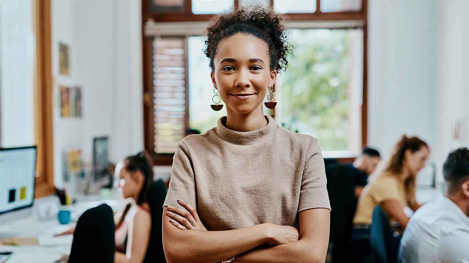 Woman standing proudly with her arms crossed in an office
